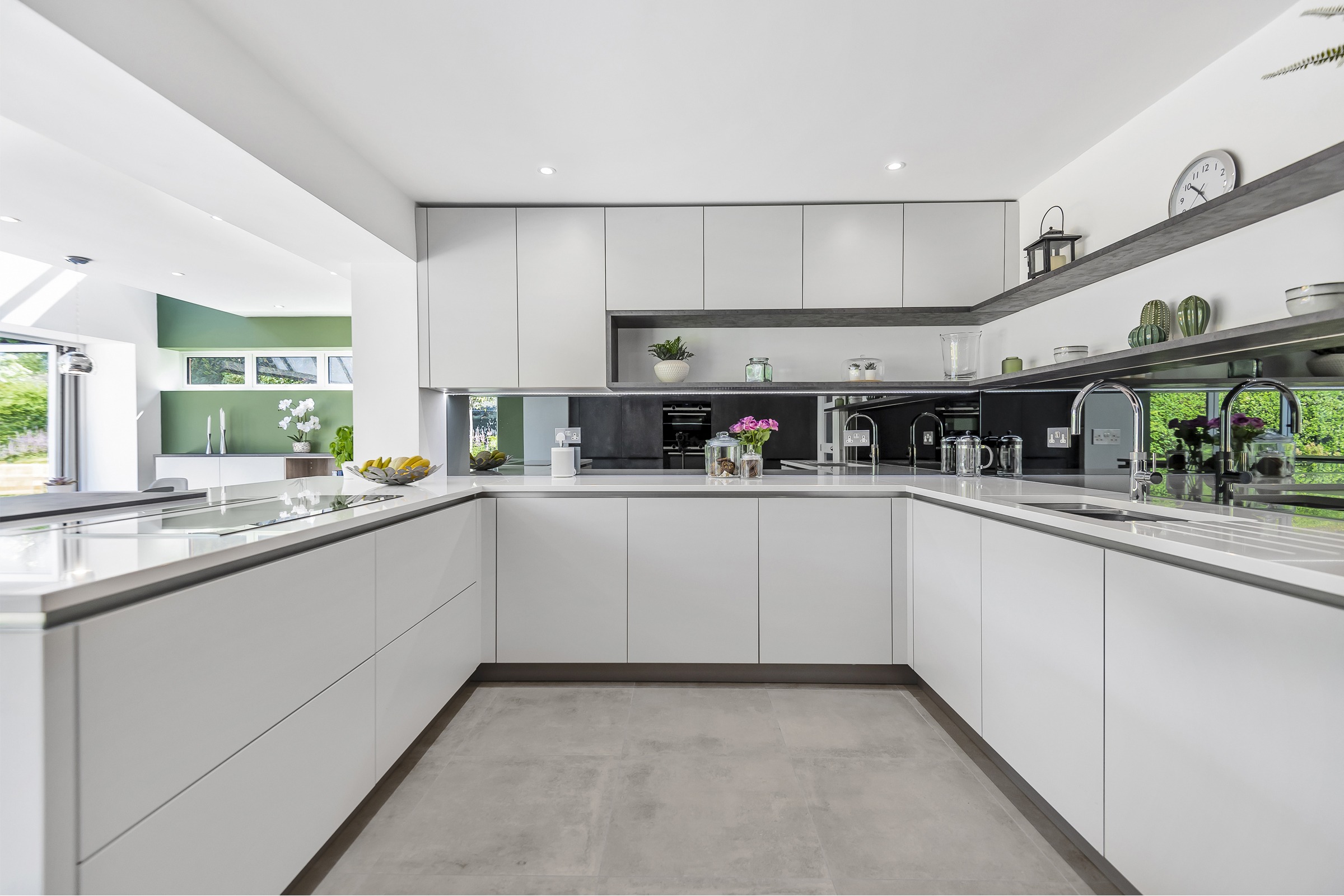 white sleek u-shape kitchen with mirror splashback