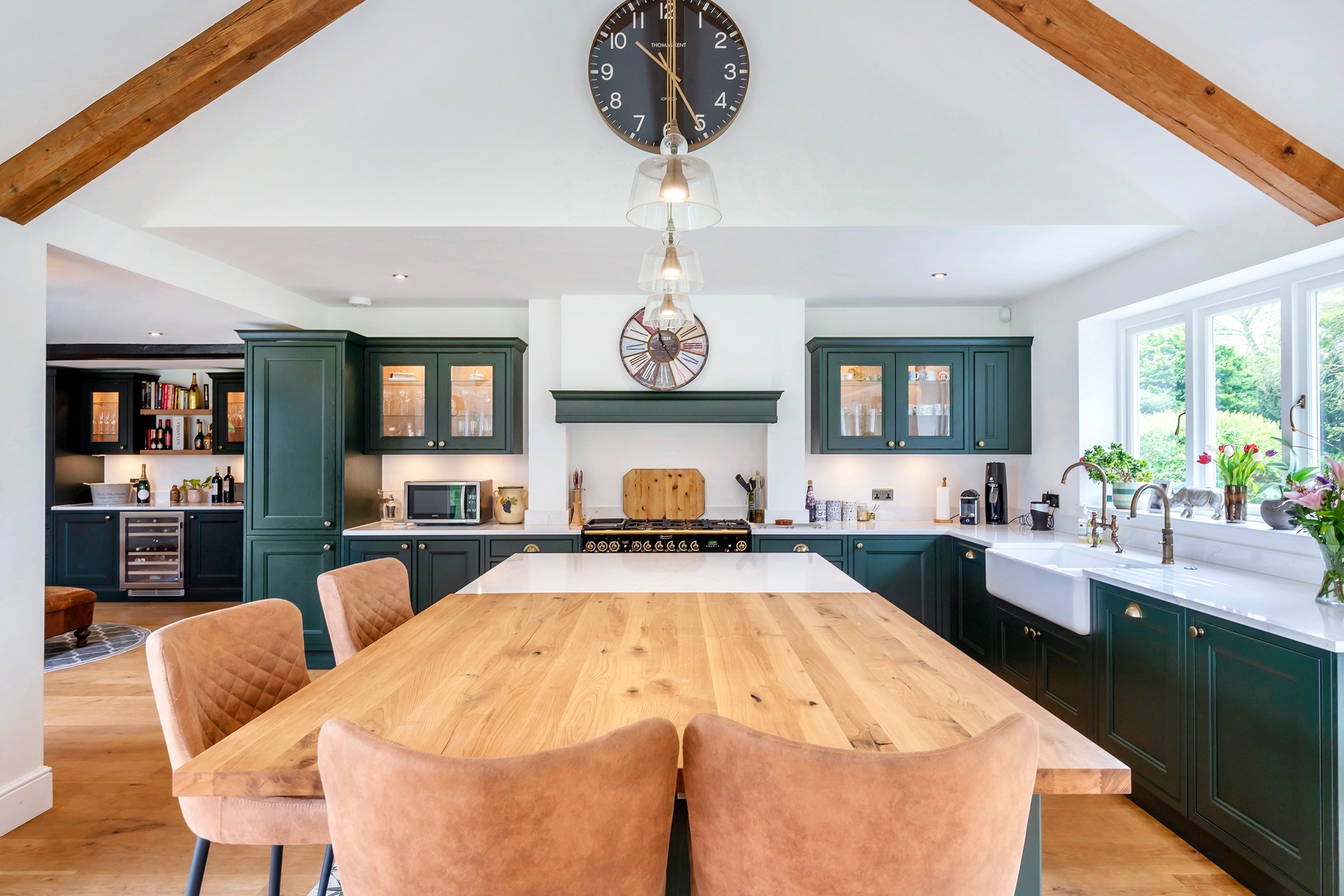 green shaker kitchen with oak dining table and ceiling beams