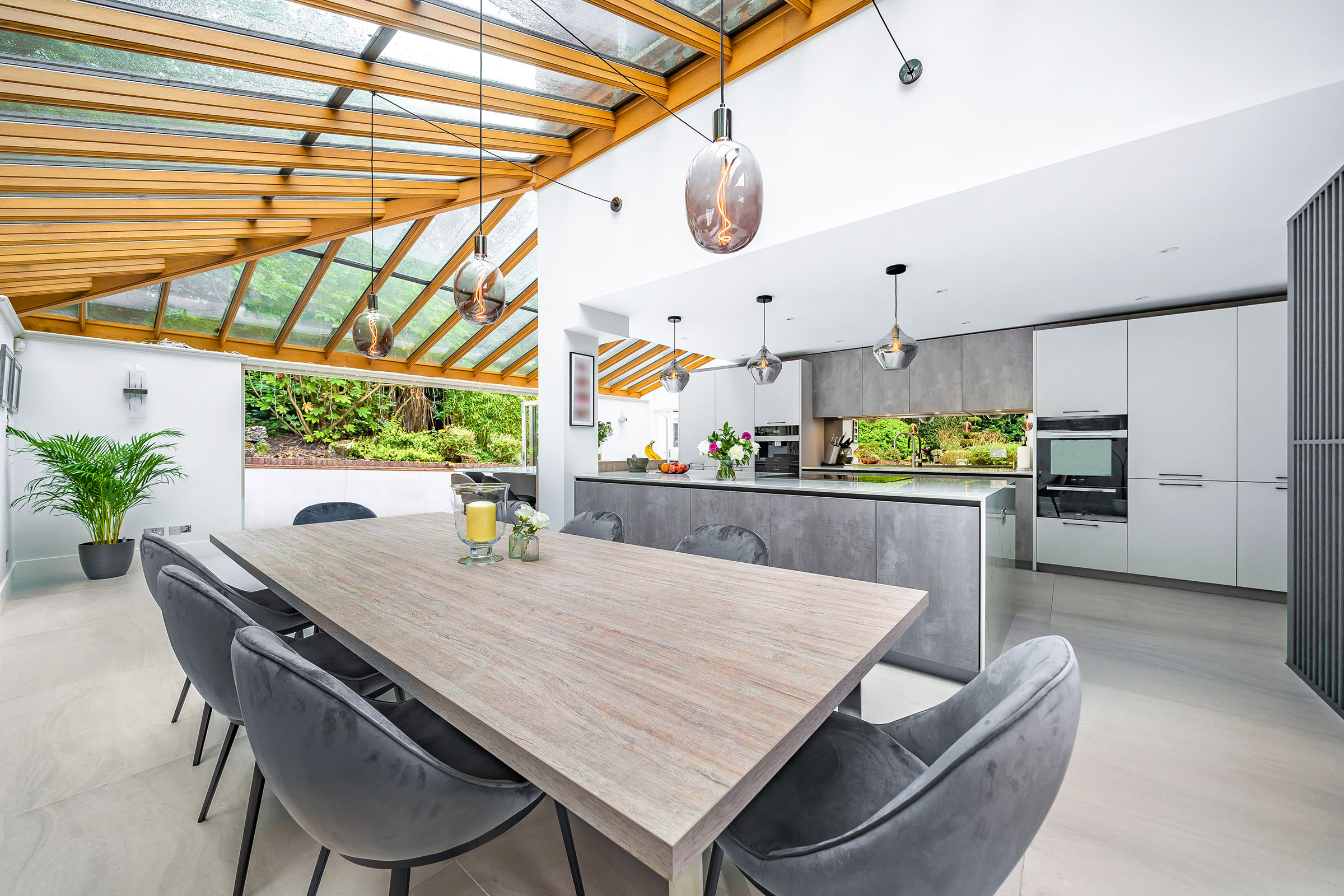 large modern grey and white kitchen extension with glass roof and wooden beams