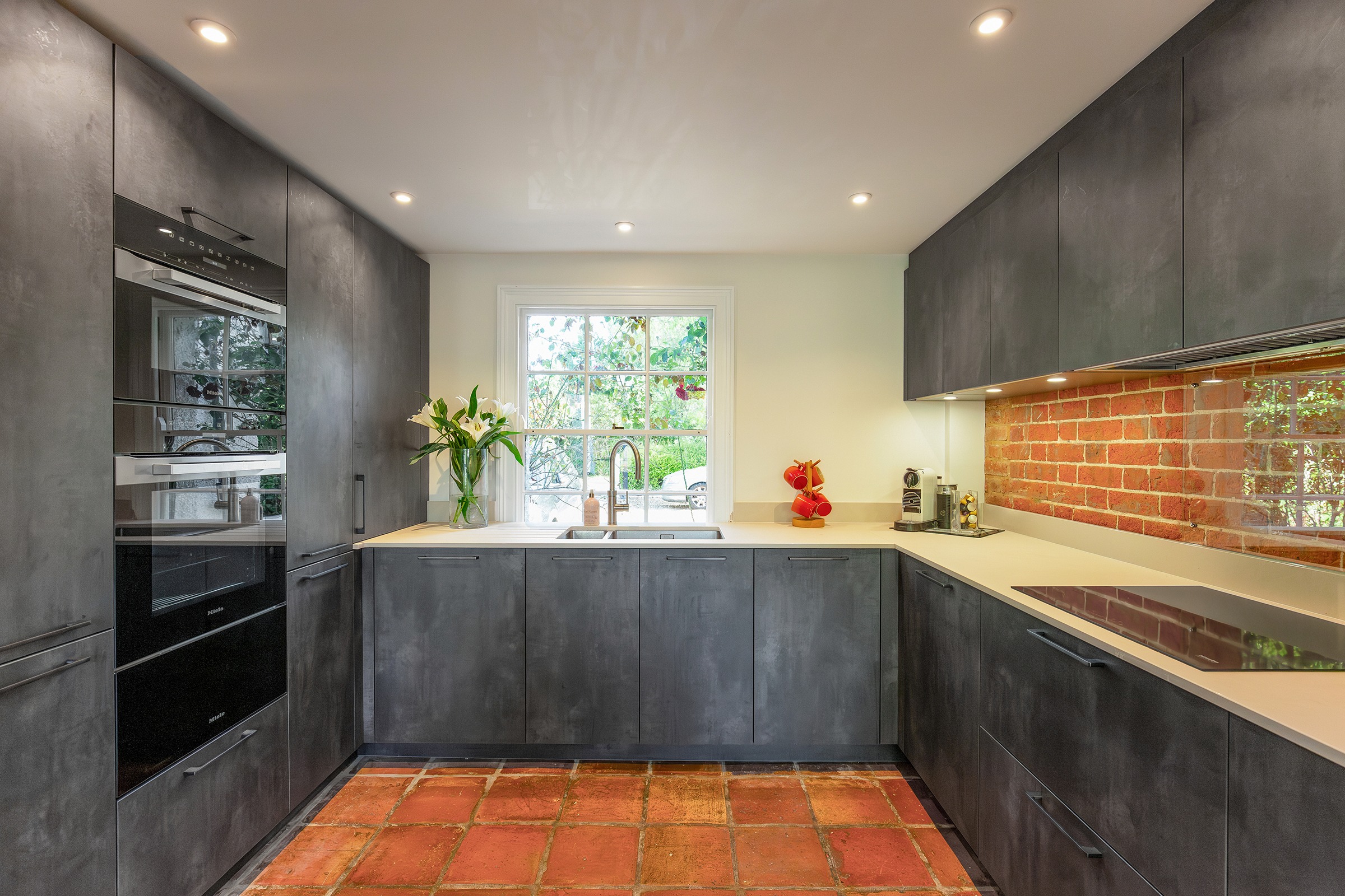 dark grey kitchen with terracotta tiled floor