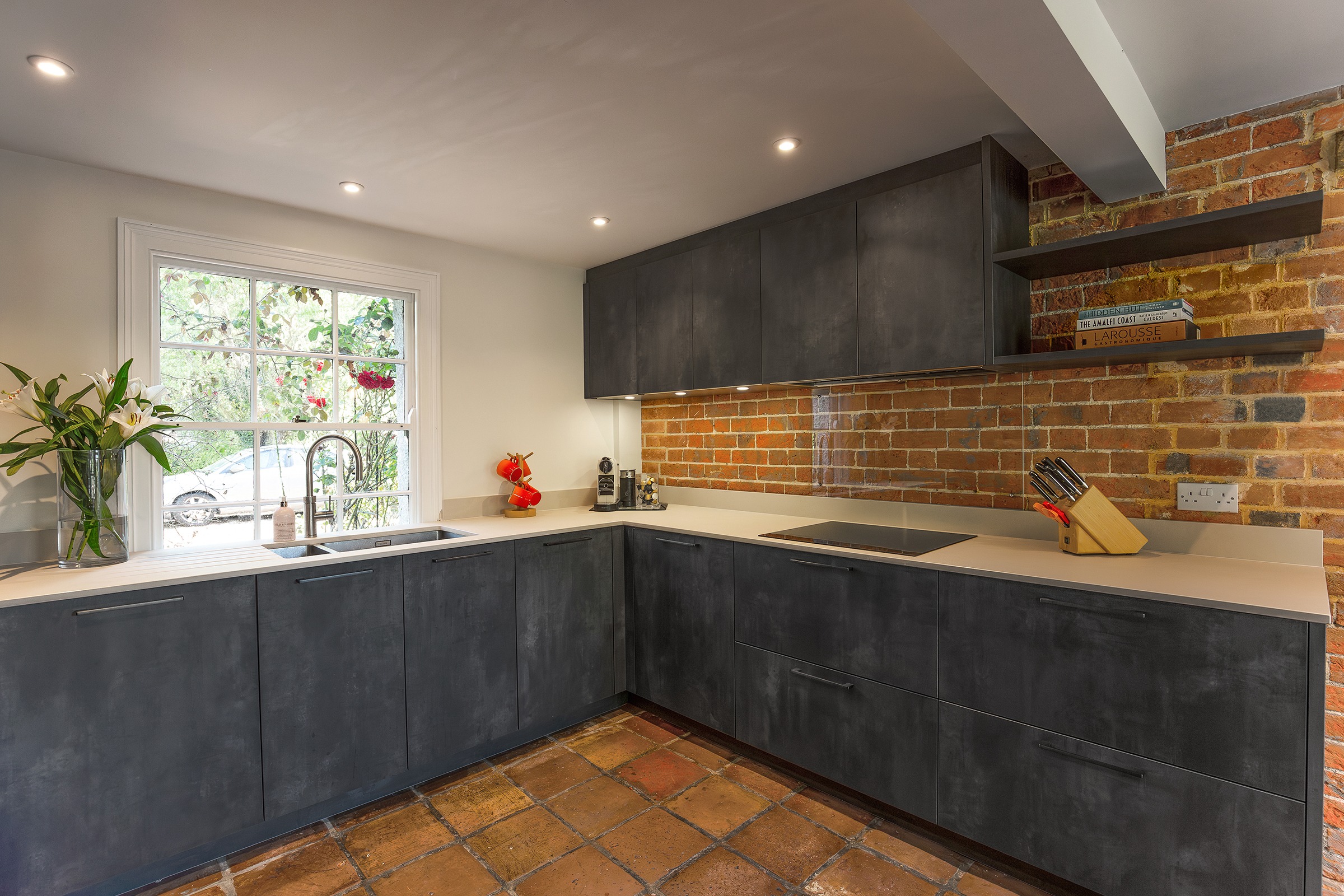dark grey kitchen with exposed brick wall and floating shelves