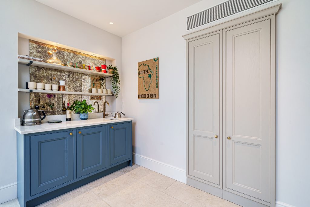 blue shaker breakfast area with a sink and antique mirror feature panel with open shelving