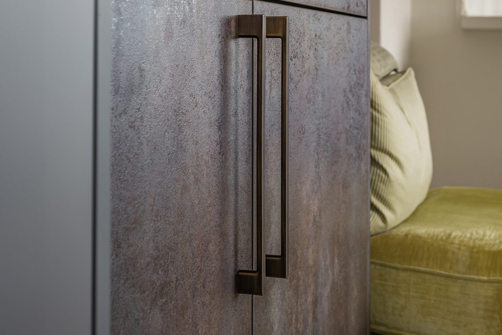 bronze bar handle on textured rust finish kitchen cabinets