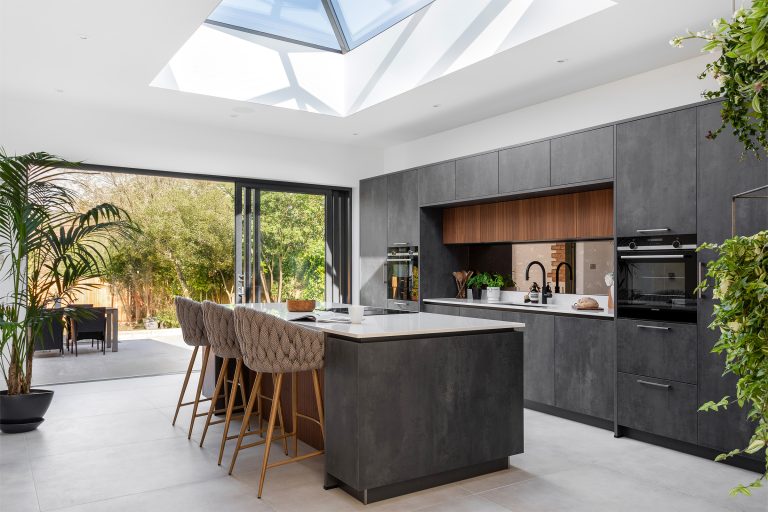 Large dark grey concrete kitchen with Walnut details and bifold doors to the gardens space.