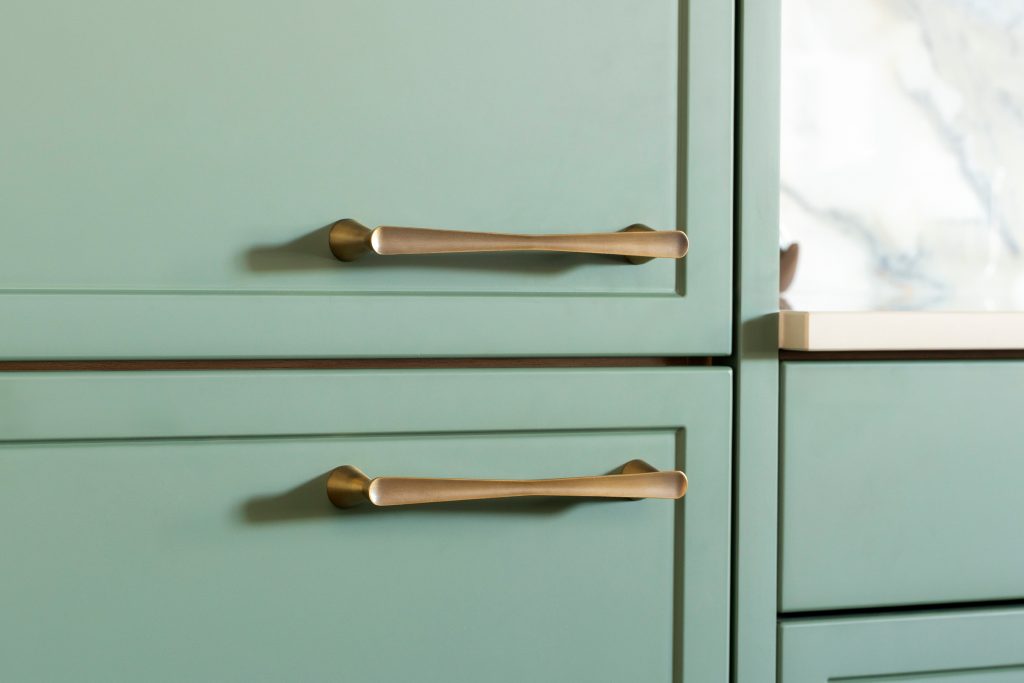 Detail of Eucalyptus Green kitchen cabinetry by KCA featuring slim shaker design and brushed brass handles, showcasing craftsmanship and attention to detail in modern trade kitchens.