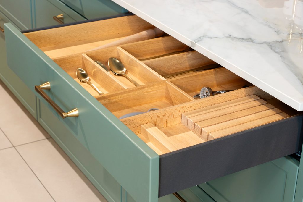 Close-up of kitchen drawers with natural oak interior and precision dividers, designed by KCA to showcase intelligent storage and German engineering for trade developments.