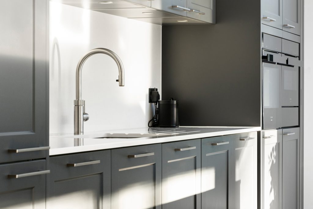 Dark modern Hacker cabinetry in a Shaker style with off-white engineered quartz worktops and Quooker tap.