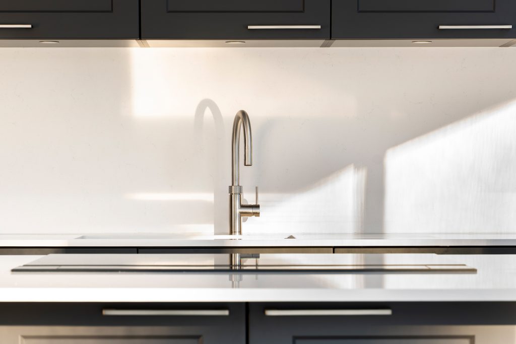 Stainless steel Quooker tap paired with refined quartz worktops in a modern shaker kitchen.
