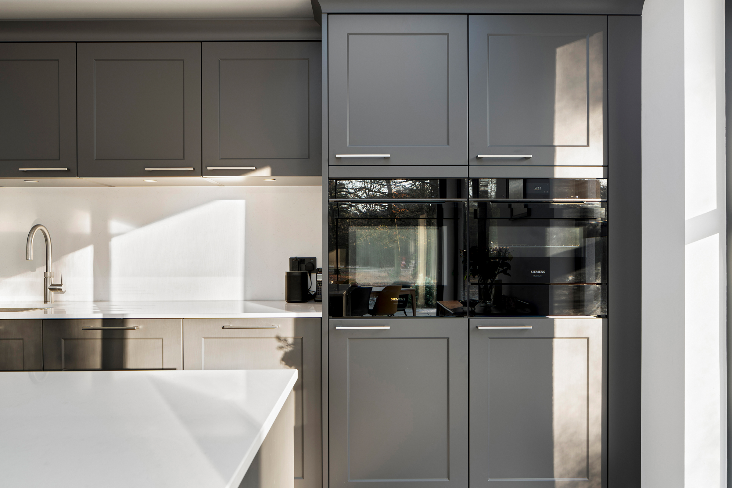 Contemporary shaker kitchen featuring Siemens integrated appliances, larder storage, Quooker boiling water tap and engineered stone worktops.