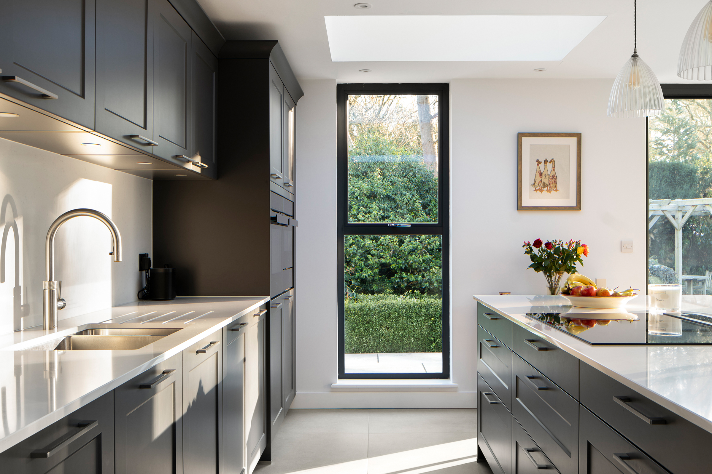 Contemporary shaker kitchen designed to maximise natural light, featuring a large window and rooflight within an open-plan extension.