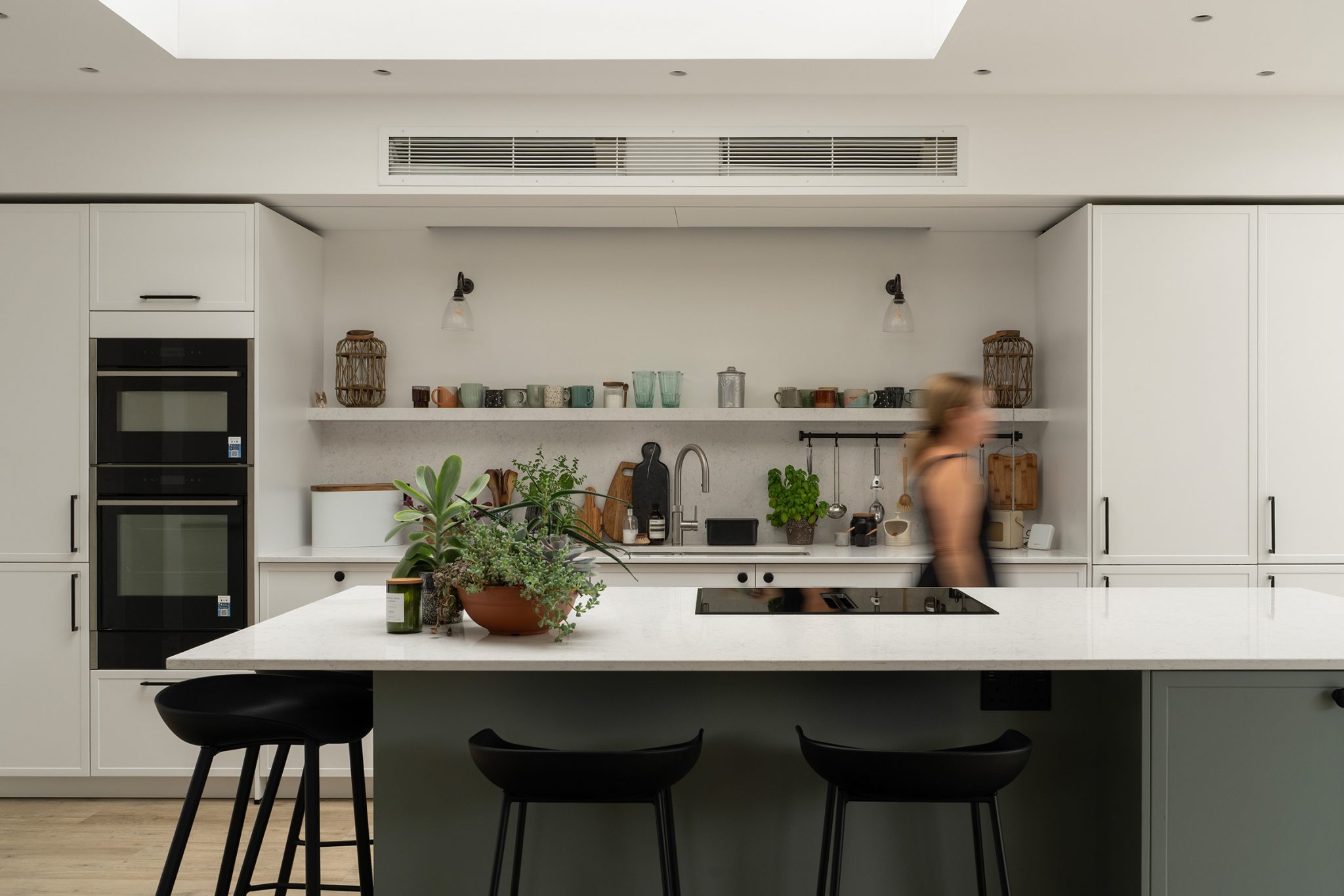 Modern slim Shaker kitchen in Crowthorne with two-tone cabinetry, large island, quartz worktops and stone floating shelf.